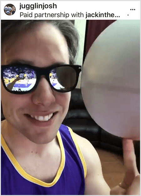 Josh Horton postează o fotografie pentru o campanie cu Jack in the Box și LA Lakers. Josh poartă ochelari de soare oglindați și un tricou Lakers și zâmbește pentru cameră în timp ce învârte o minge.